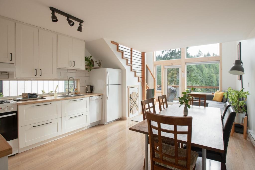 a kitchen with white cabinets and a table with chairs at Le Chalet Waterfront Retreat in Ucluelet
