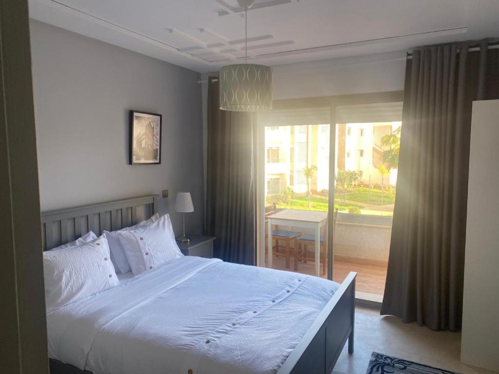 ein Schlafzimmer mit einem großen Bett und einem großen Fenster in der Unterkunft Marina Saidia Luxury Apartment with pool & Garden view. Residence Tamaris in Saidia 
