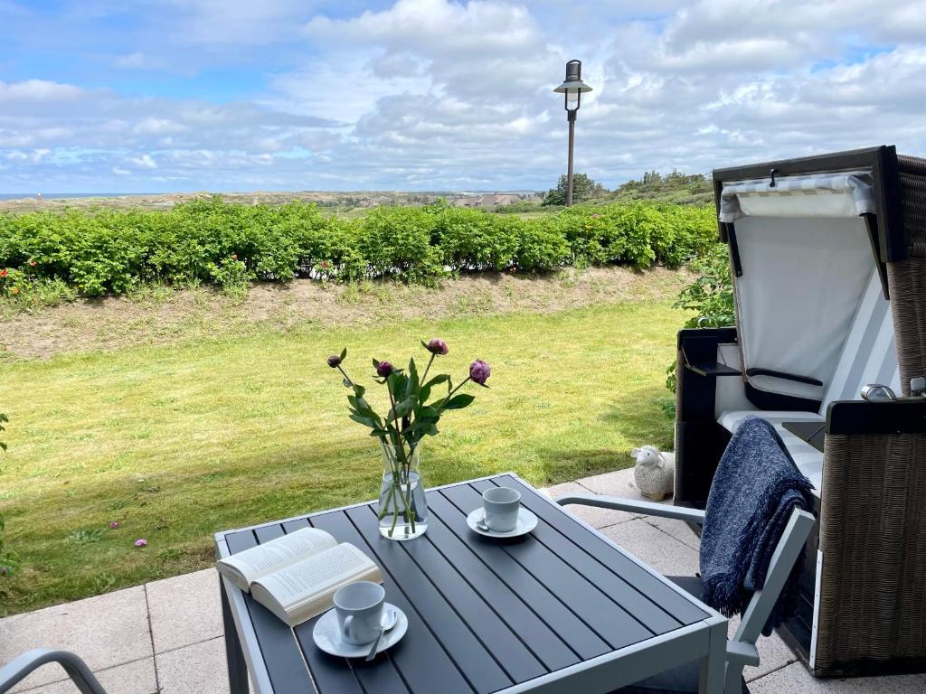 a blue table with a vase of flowers on a patio at Haus Kampbarg Suite 2-Meer-Blick in Kampen