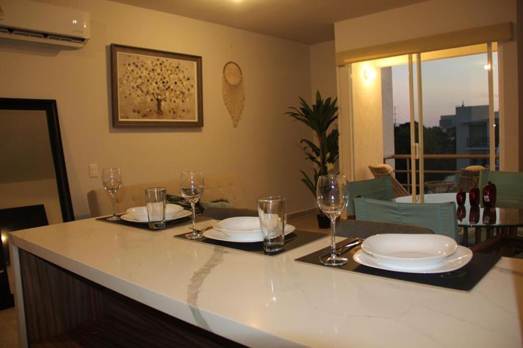 a kitchen with a table with plates and wine glasses at Departamento en zona diamante Acapulco in Acapulco