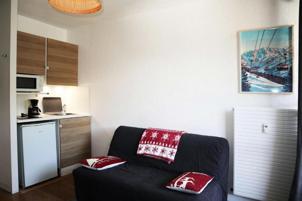 a living room with a black couch with red pillows at Résidence Le Boussolenc - JOLI STUDIO CENTRE STATION MAE-2134 in Le Mélézet