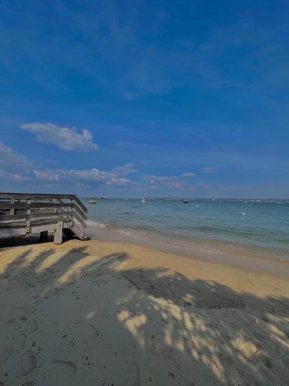 une jetée en bois sur une plage avec l'océan dans l'établissement Cabane Claouey, bassin Cap ferret, à Claouey
