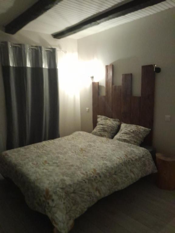 une chambre avec un grand lit avec une tête de lit en bois dans l'établissement Maison en pierre rouge du vallon, à Valady