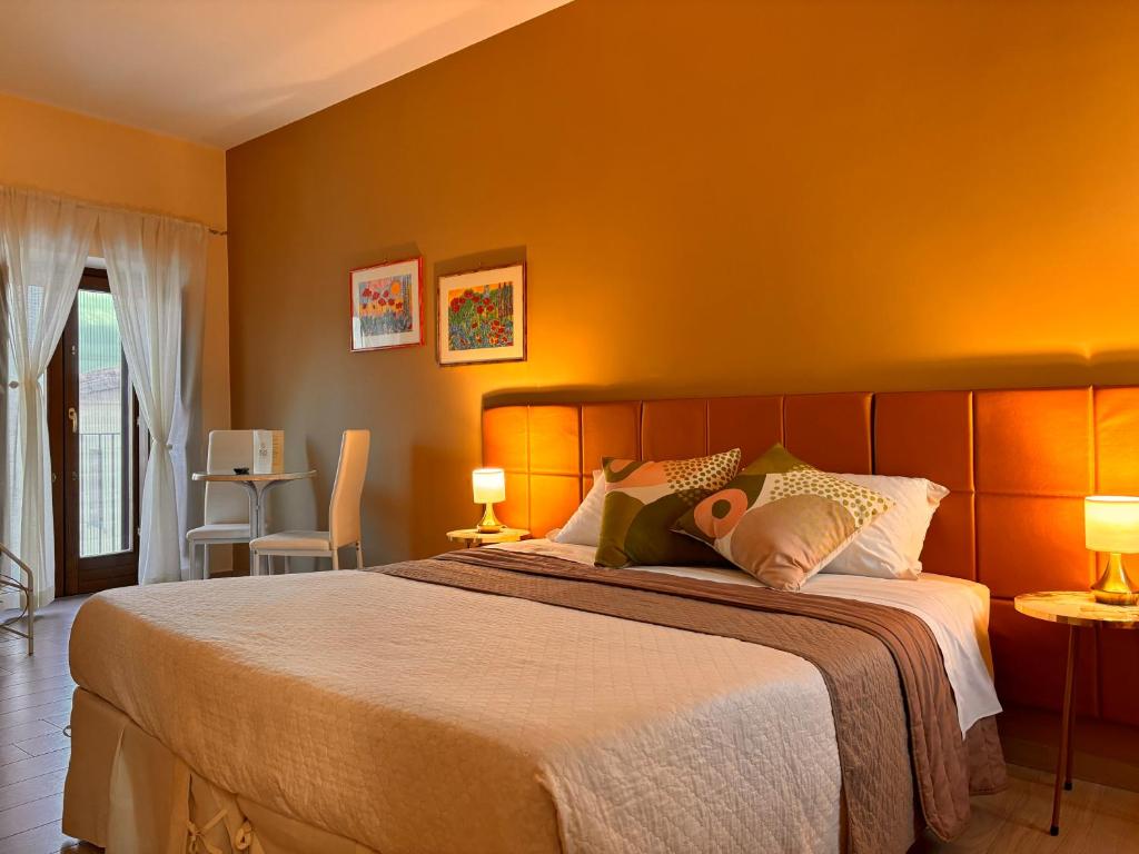1 dormitorio con 1 cama grande y paredes de color naranja en Dimora Offidius, en LʼAquila