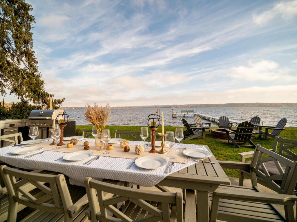 a table with plates and wine glasses and a view of the water at Casa Andante - Lakefront Escape in Mayville