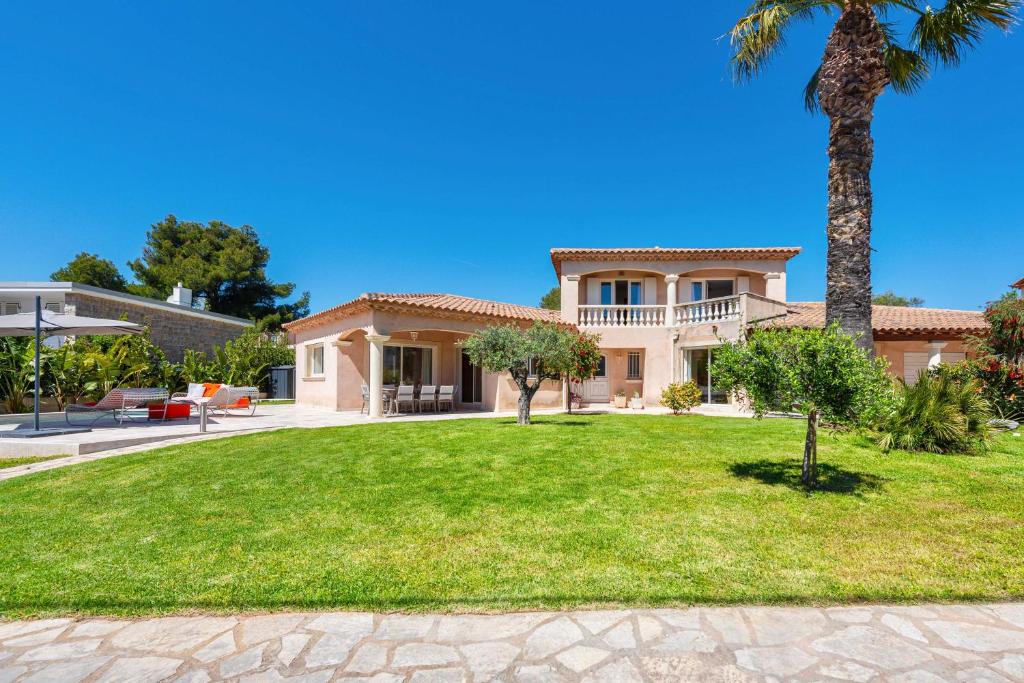 une maison avec un palmier et une cour dans l'établissement Villa Pitou, Piscine chauffée, 200m plage, à La Londe-les-Maures