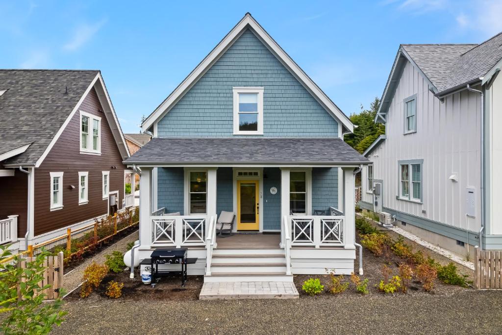 a blue house with a porch and two white houses at Dogwood Cottage by Seabrook Hospitality in Pacific Beach
