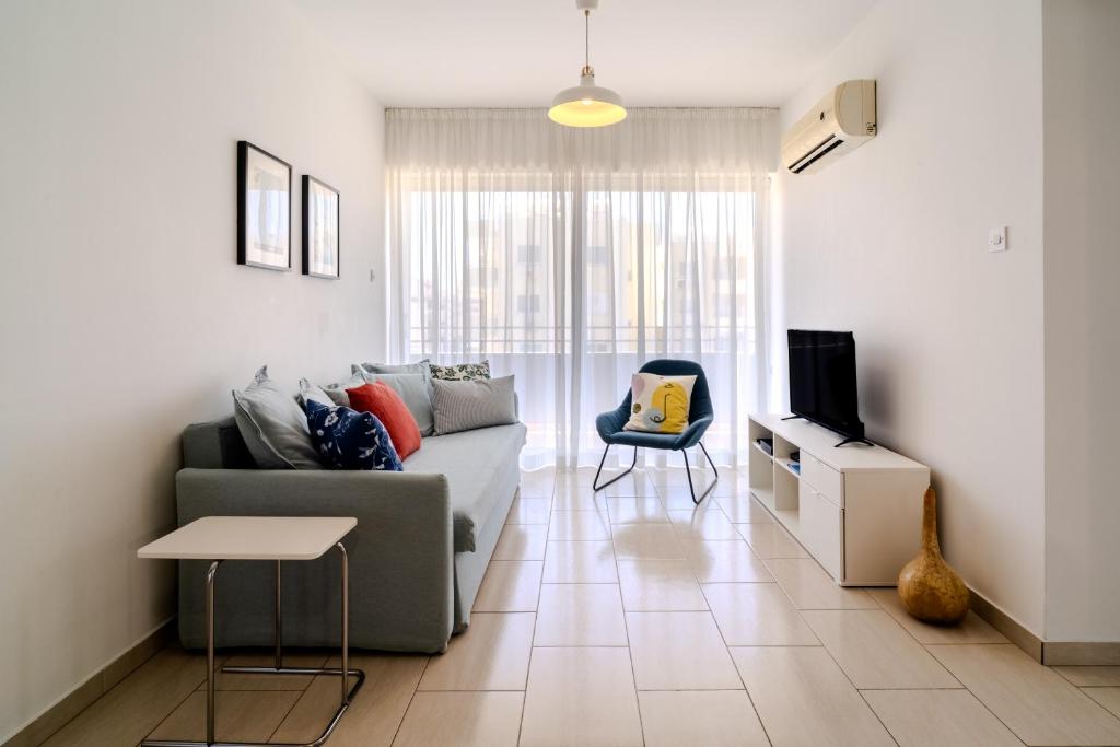 un soggiorno con divano e TV di Athina Mackenzie 2 Bedroom Flat with Pool a Larnaka