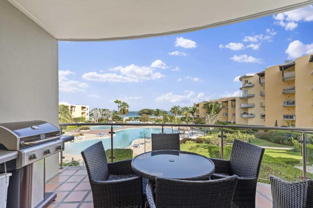 balcón con mesa, sillas y vistas a la piscina en Beachfront - Summer View 2BR condo - A244, en Palm-Eagle Beach