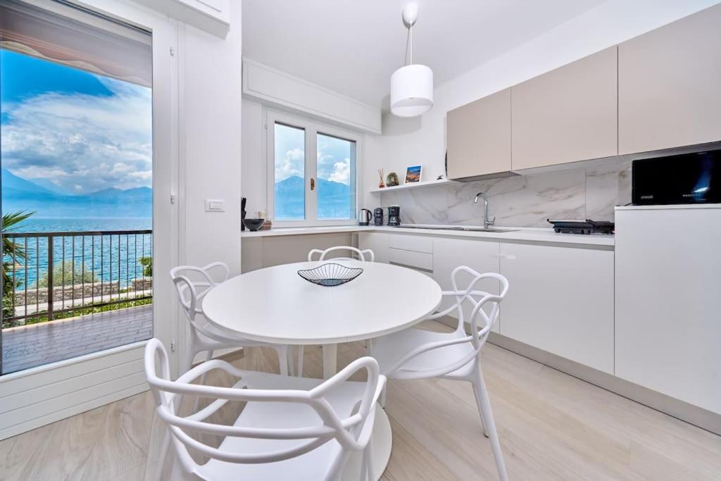 a white kitchen with a white table and chairs at Benaco Hause 3 in Brenzone sul Garda