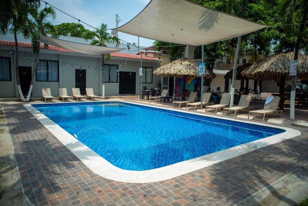 San Luis的住宿－Mi Tierra Hotel y Restaurante，一个带椅子和遮阳伞的大型蓝色游泳池