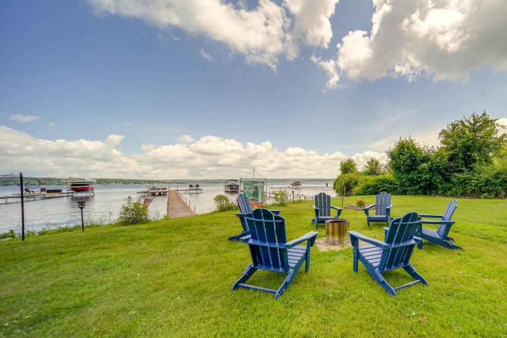 un grupo de sillas azules sentadas en la hierba junto al agua en Lakefront Mayville Cottage with Dock and Grill! en Mayville