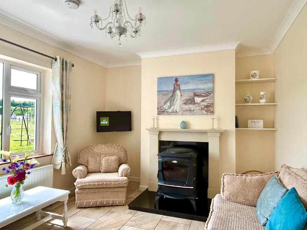 uma sala de estar com lareira e um lustre em Breenville Farm House em Tralee