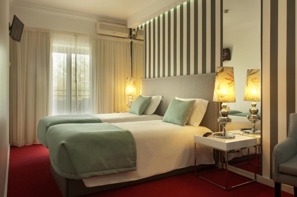 ファティマにあるHotel Lagoa dos Pastorinhosの大きなベッドとテーブルが備わるホテルルームです。