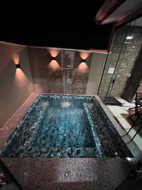 a swimming pool with a fountain in the middle at Casa Suítes Beach in Vilhena