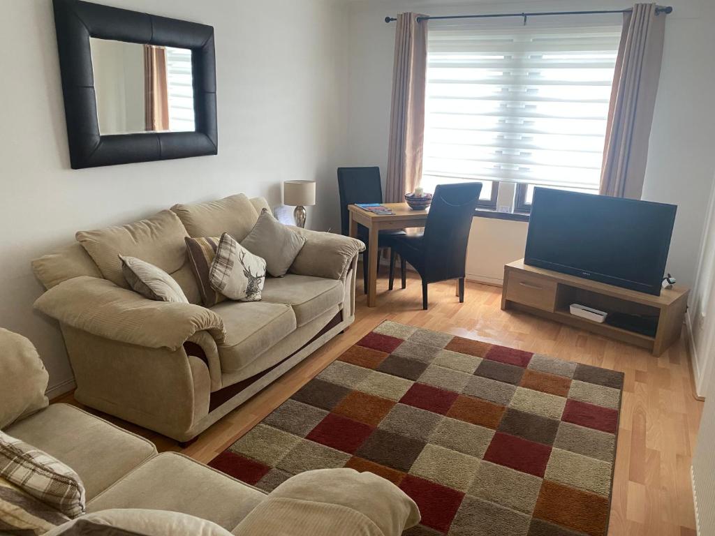 salon z kanapą i telewizorem w obiekcie Argyll Apartment Loch Lomond w mieście Balloch