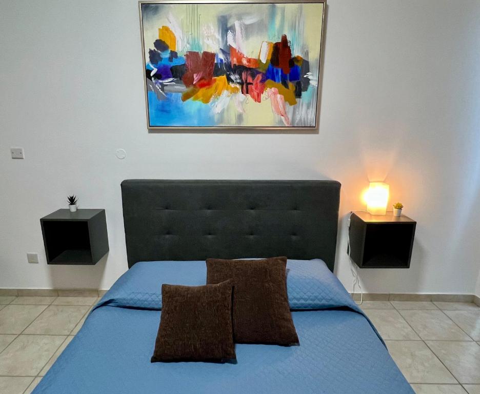 a bedroom with a blue bed and a painting on the wall at FatCow Seaside Suites in Livadhia