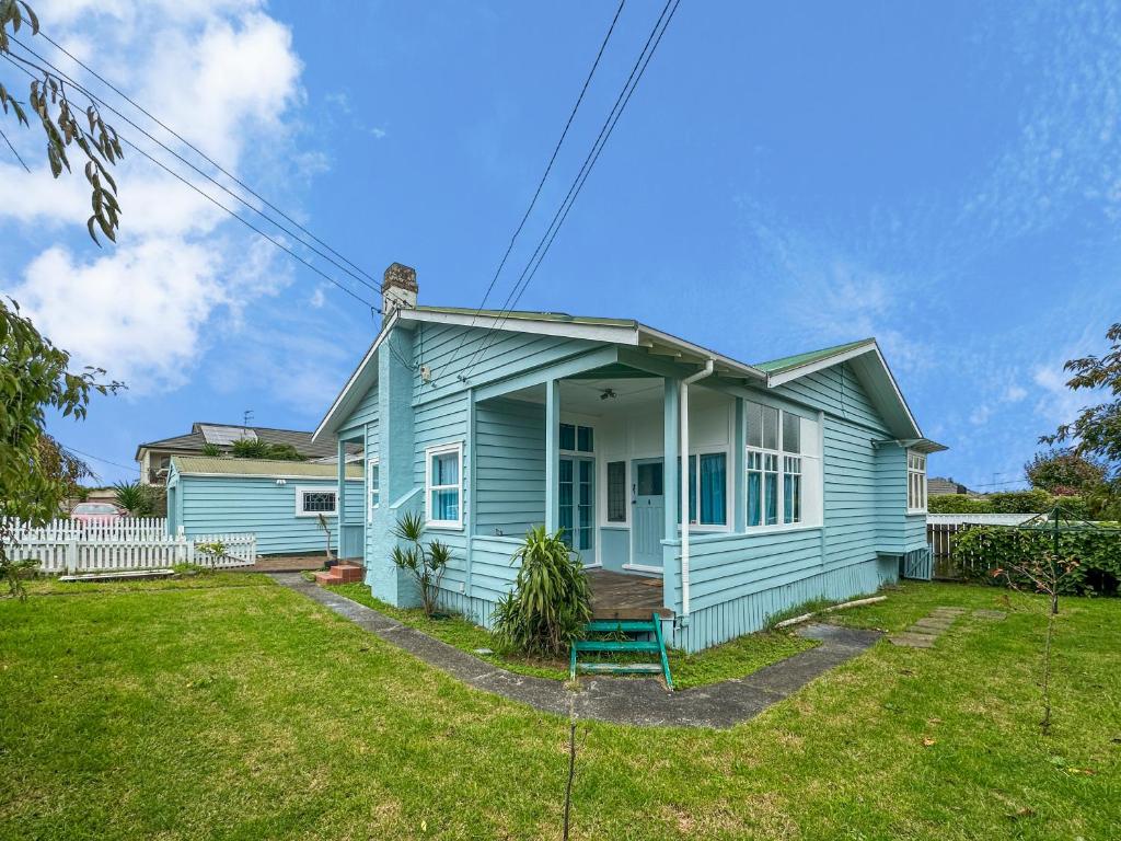 a blue house with a porch and a yard at Green Getaway- Unique, 4 bedroom Bungalow Papakura in Auckland
