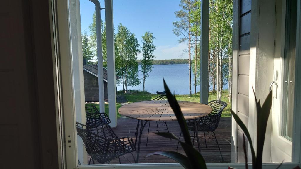 un patio con mesa y sillas y vistas al lago en Hanhi Linna en Taivalkoski