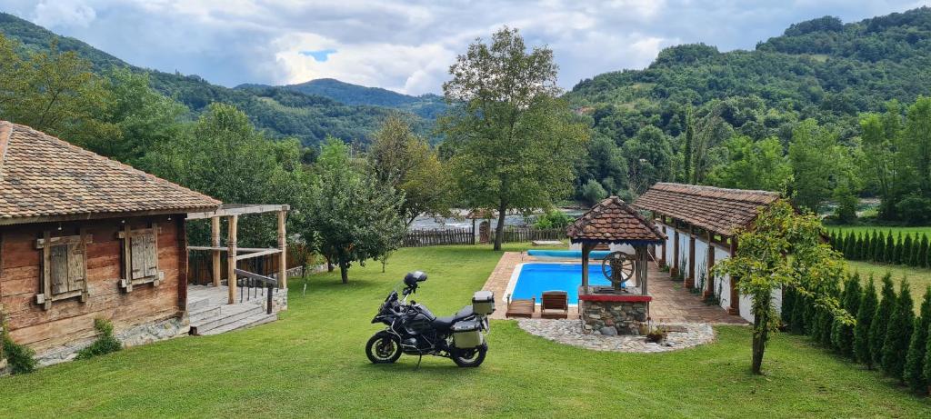 a motorcycle parked next to a house and a swimming pool at Drinsko selo Ovčinja in Ovčinja