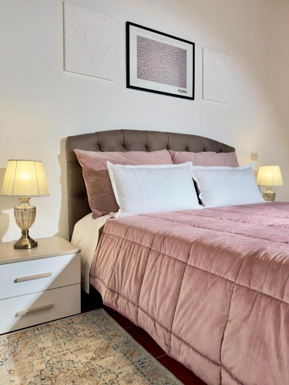 a bedroom with a pink bed and a night stand with a lamp at Il cretto bianco in Città di Castello