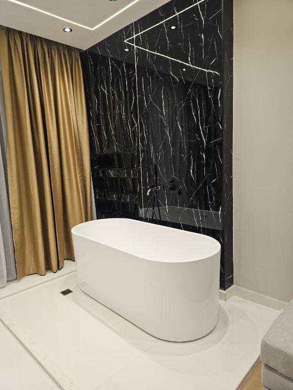 a white tub in a room with a black wall at Diol Hotel Ksamil in Ksamil