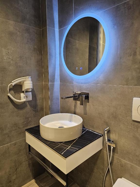 a bathroom with a sink and a round mirror at Diol Hotel Ksamil in Ksamil
