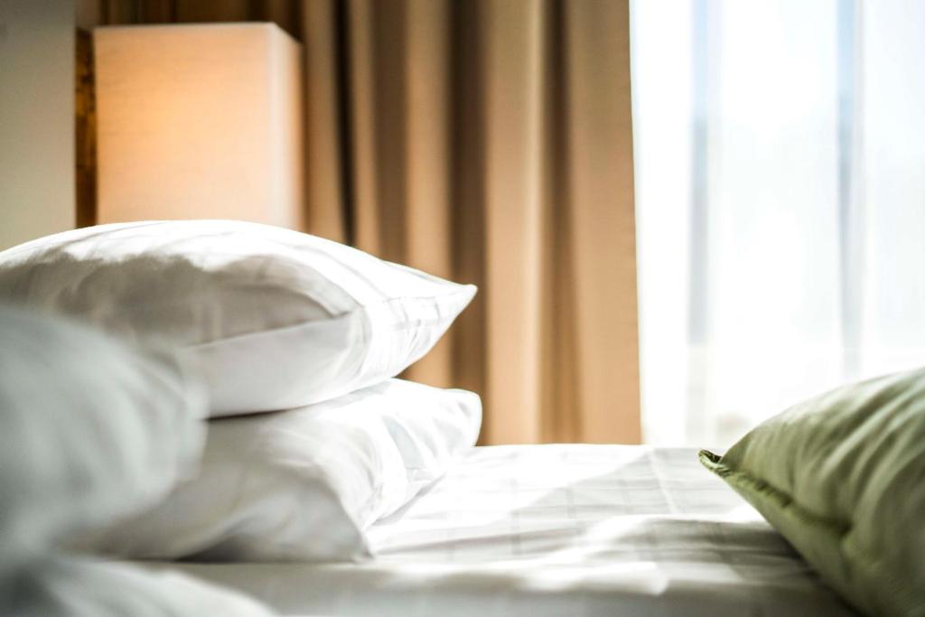 1 cama con almohadas blancas y ventana en Scandic Lahti City en Lahti