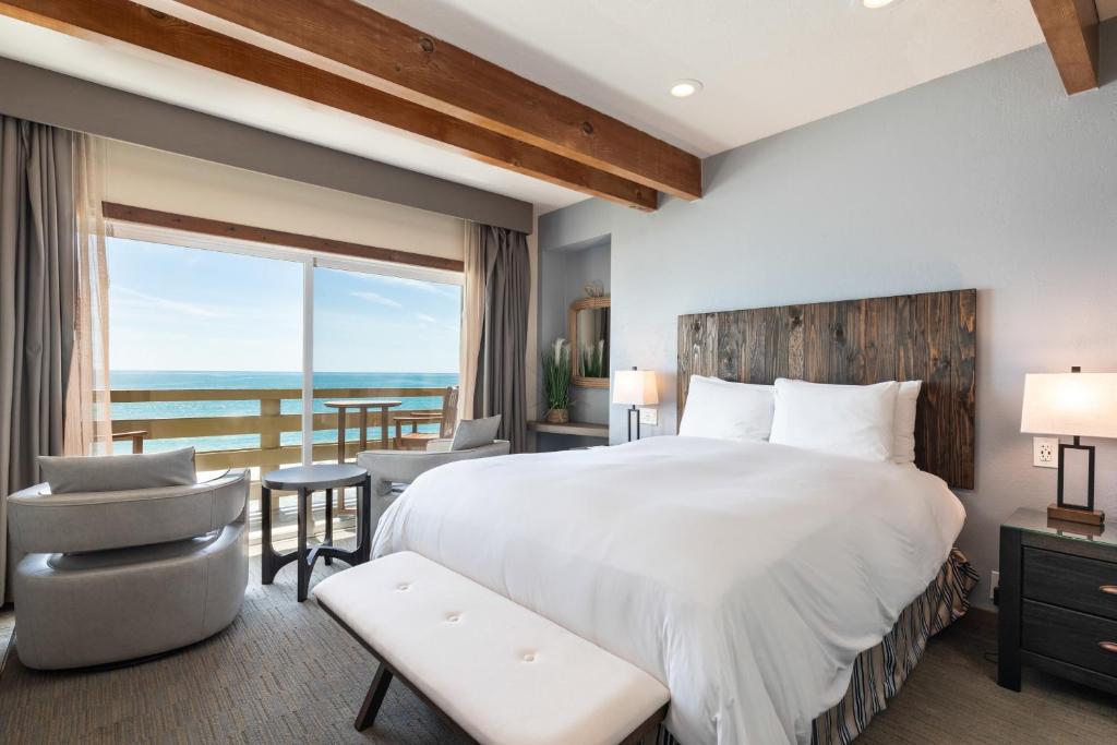 1 dormitorio con 1 cama grande y balcón en Cypress Inn on Miramar Beach, en Half Moon Bay