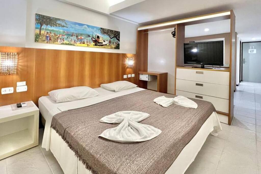 une chambre avec deux lits et une télévision à écran plat dans l'établissement Apartamento Beira Mar centro Pipa com Piscina vista mar completo, à Pipa