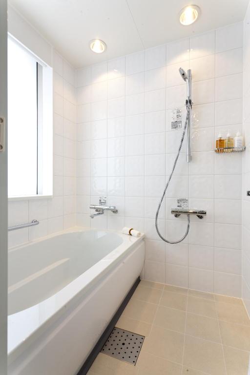 a white bathroom with a tub and a shower at Solaria Nishitetsu Hotel Ginza in Tokyo