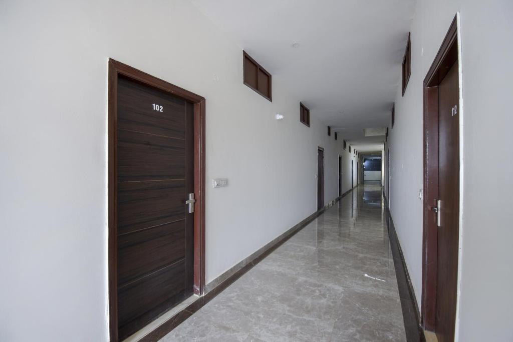 um corredor com duas portas de madeira e um corredor com piso de azulejo em Flagship 71214 Hotel Welcome Inn em Ludhiana