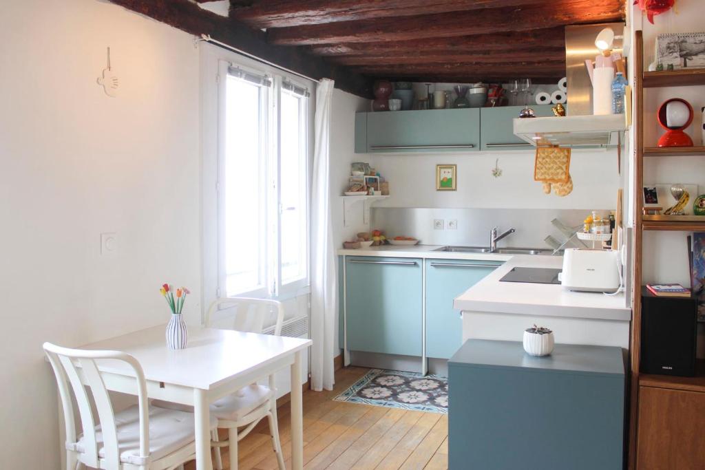 - une cuisine avec une table et une table et des chaises blanches dans l'établissement Bright and quiet 25 m apartment, à Paris