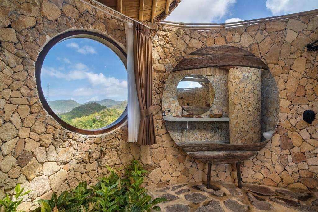 Zimmer mit kreisförmigem Fenster in einer Steinwand in der Unterkunft Villa Grazia - Anima Eco Lodge -Ville Lussuose con Piscina Vista Mare in Selong Belanak