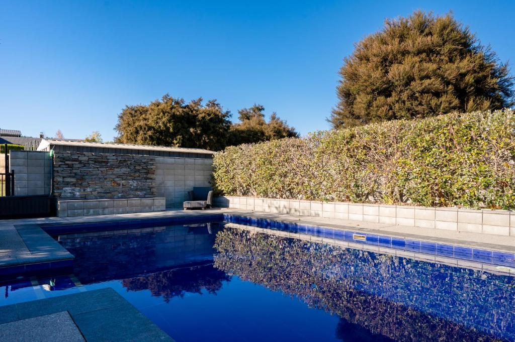 a swimming pool in front of a hedge at Beacon Point Retreat by Sotheby's Luxury Rental Homes in Wanaka