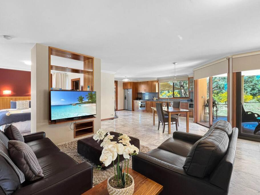 un soggiorno con 2 divani neri e una TV di Aurora Cottages - Six Seasons a Pomonal