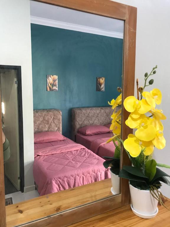 a mirror in a bedroom with a bed and flowers at Zaz cottage Langkawi in Pantai Cenang