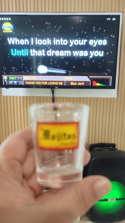 a person holding a glass in front of a computer monitor at Olango Transient Home,with WIFI &Netfix in Santa Rosa