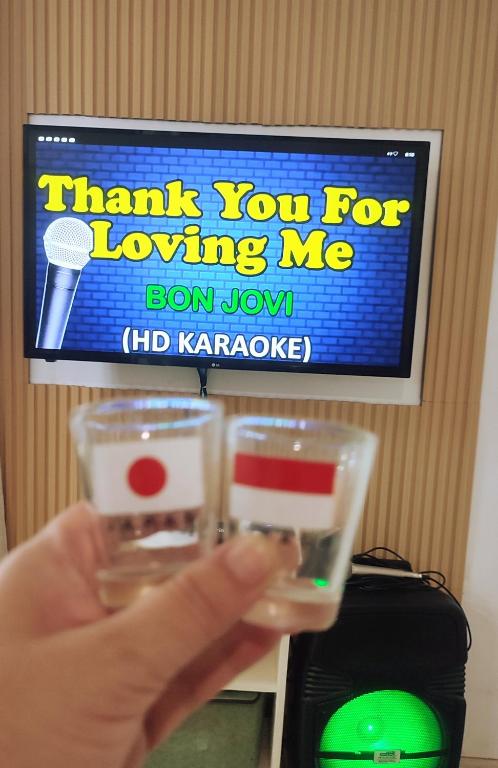 a person holding two wine glasses in front of a television at Olango Transient Home,with WIFI &Netfix in Santa Rosa