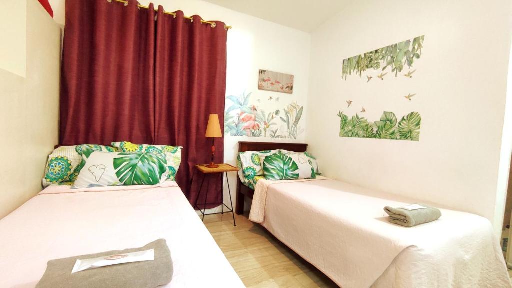two beds in a room with red curtains at Olango Transient Home,with WIFI &Netfix in Santa Rosa