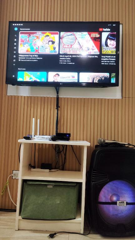 a flat screen tv hanging on a wall with a table at Olango Transient Home,with WIFI &Netfix in Santa Rosa