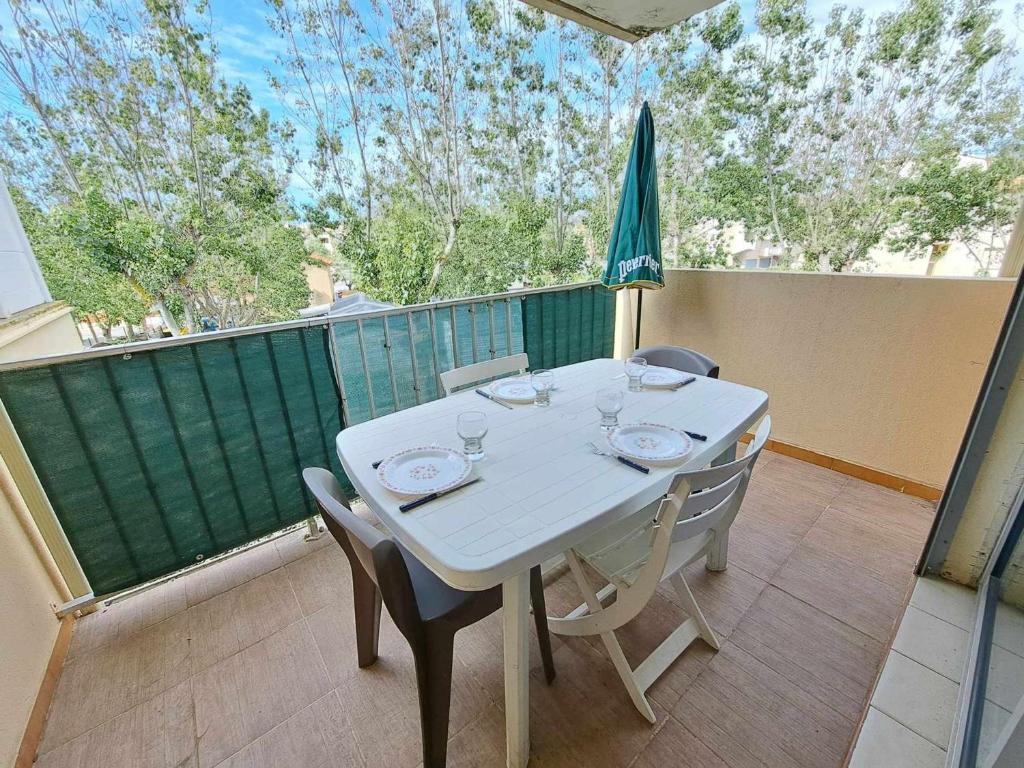 d'une table blanche avec des chaises et un parasol sur le balcon. dans l'établissement Appartement 2 pièces accès direct plage avec parking privé - FR-1-326-823, à Marseillan