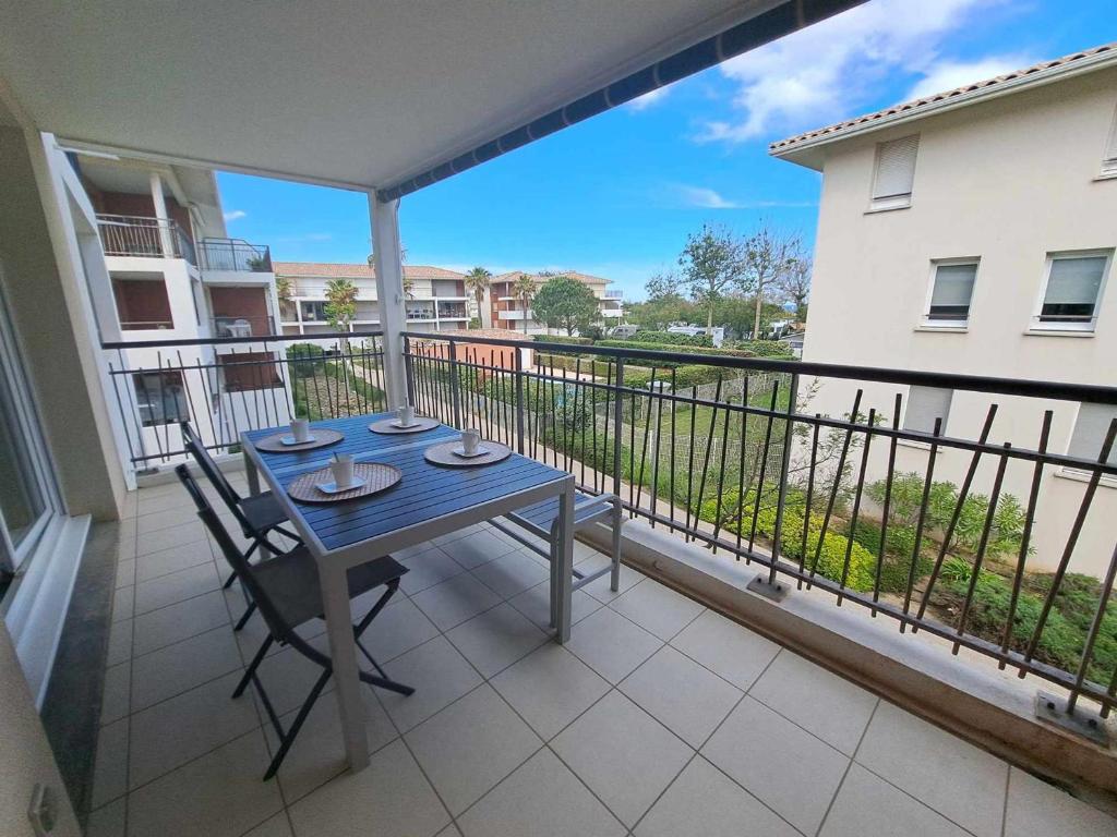 d'un balcon avec une table bleue et des chaises. dans l'établissement Appartement T2 avec Terrasse, Piscine et Parking Privé - Marseillan - FR-1-326-826, à Marseillan