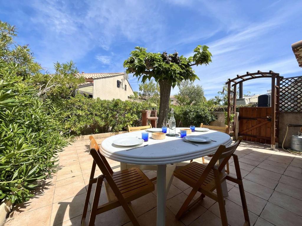 - une table blanche avec deux chaises sur la terrasse dans l'établissement Pavillon à Gruissan avec Piscine, Terrasse et Parking Privé - 4 Couchages - FR-1-229-889, à Gruissan