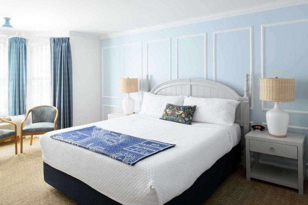 Coventry Motor Inn في سان فرانسيسكو: غرفة نوم بسرير ولحاف ابيض و ازرق