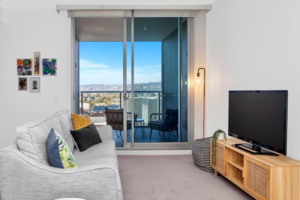 a living room with a couch and a television at 'The Hindmarsh' Hotel-style Pad with Hills Panorama in Adelaide