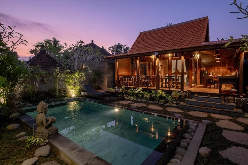 a villa with a swimming pool in front of a house at Ithaca Ubud Villa in Ubud
