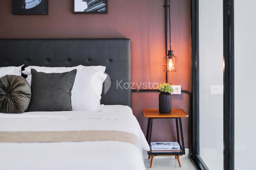 a bedroom with a bed and a side table at Sovrae by Kozystay - Grogol in Jakarta