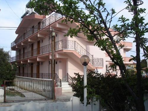 un grand bâtiment rose avec un balcon. dans l'établissement Berk Apart Hotel, à Küçükkuyu
