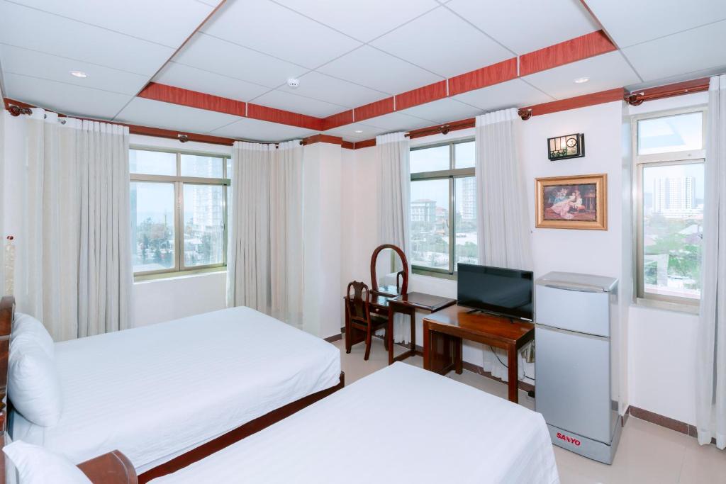 sypialnia z 2 łóżkami i biurkiem z telewizorem w obiekcie Phúc Đạt Hotel w mieście Vung Tau